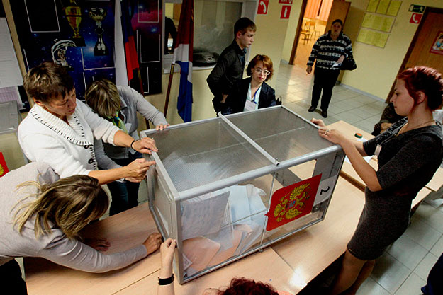 Сотрудники участковой избирательной комиссии вынимают избирательные бюллетени для подсчета голосов © РИА Новости