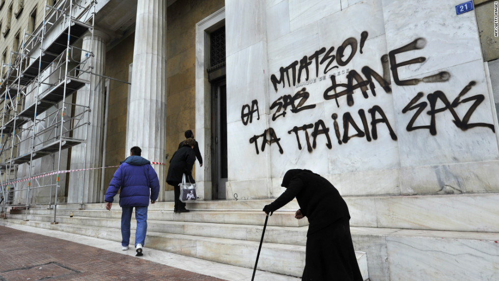 Престарелая женщина просить милостыню перед входом в национальный банк Греции. © cnn.com