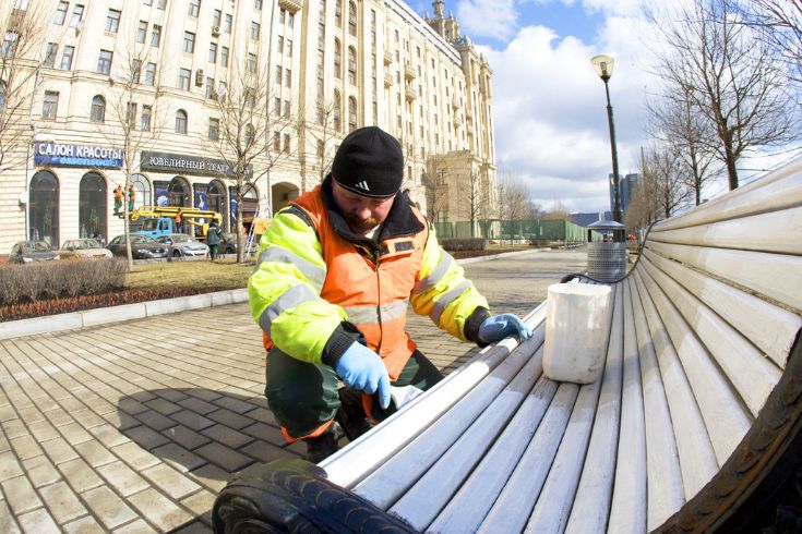 Рабочий красит скамейку в Москве © mn.ru