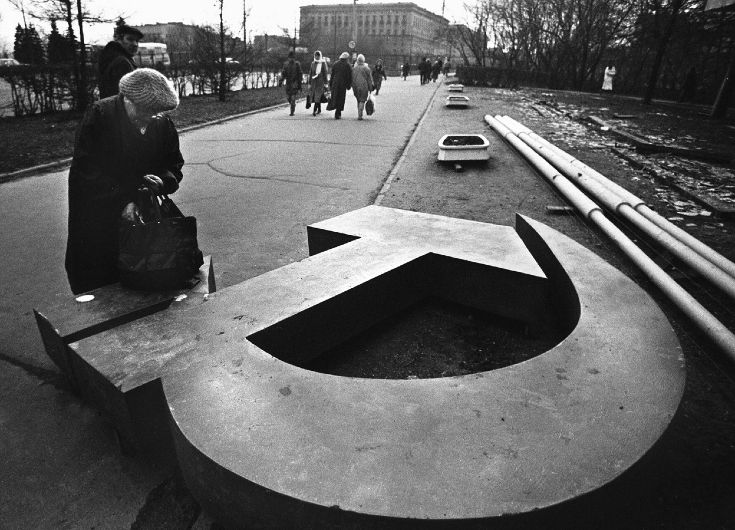 Женщина копается в сумке на демонтированном памятнике в Москве в 1991 году © theatlantic.com